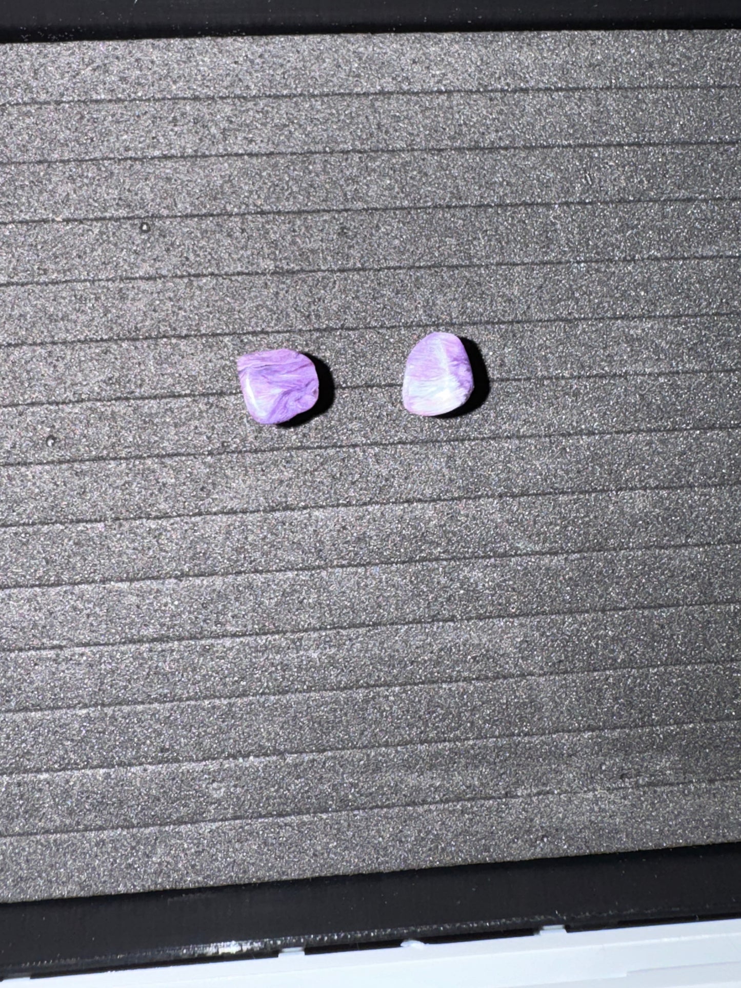 Two purple stones on a textured gray surface