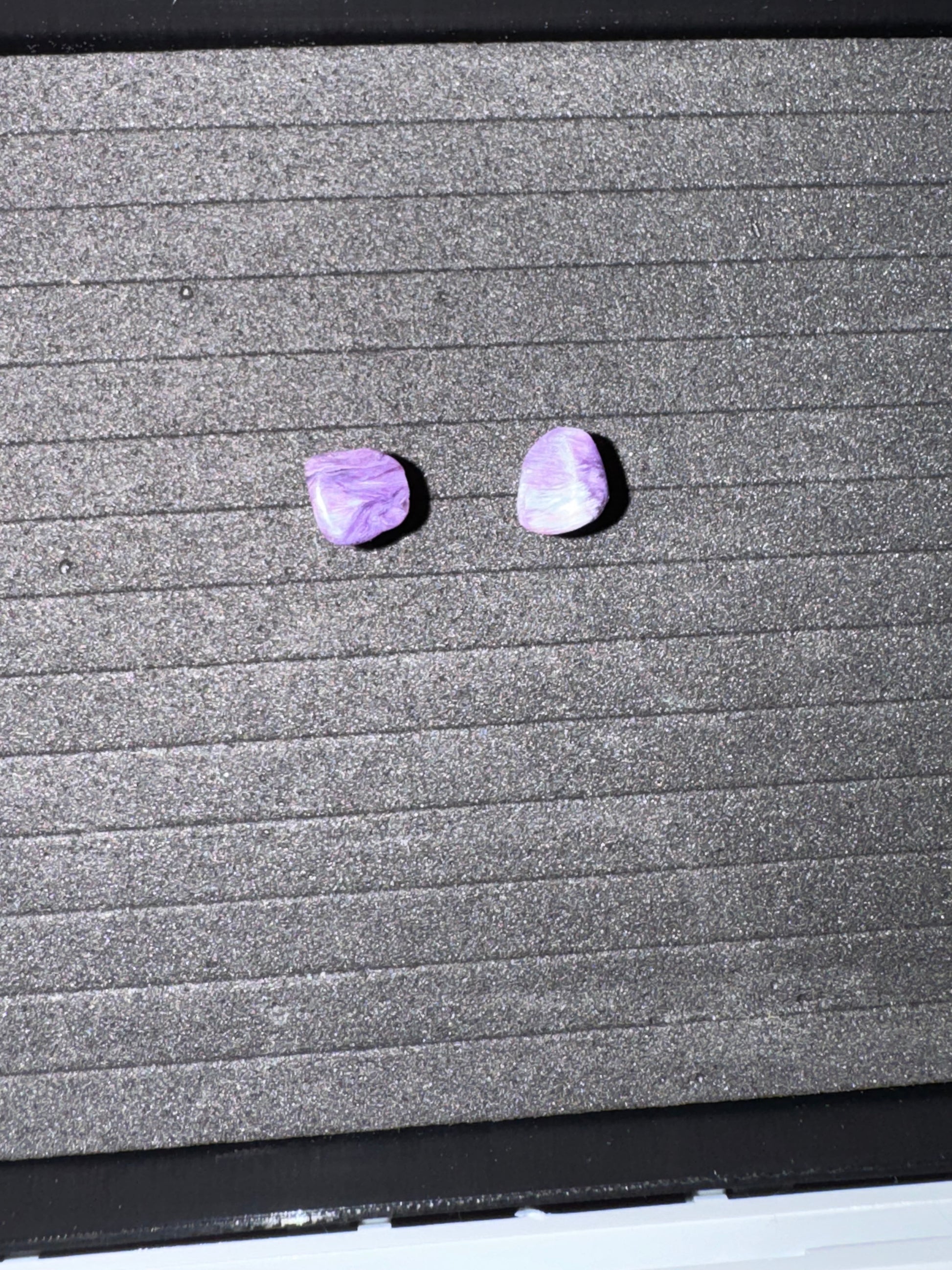 Two purple stones on a textured gray surface