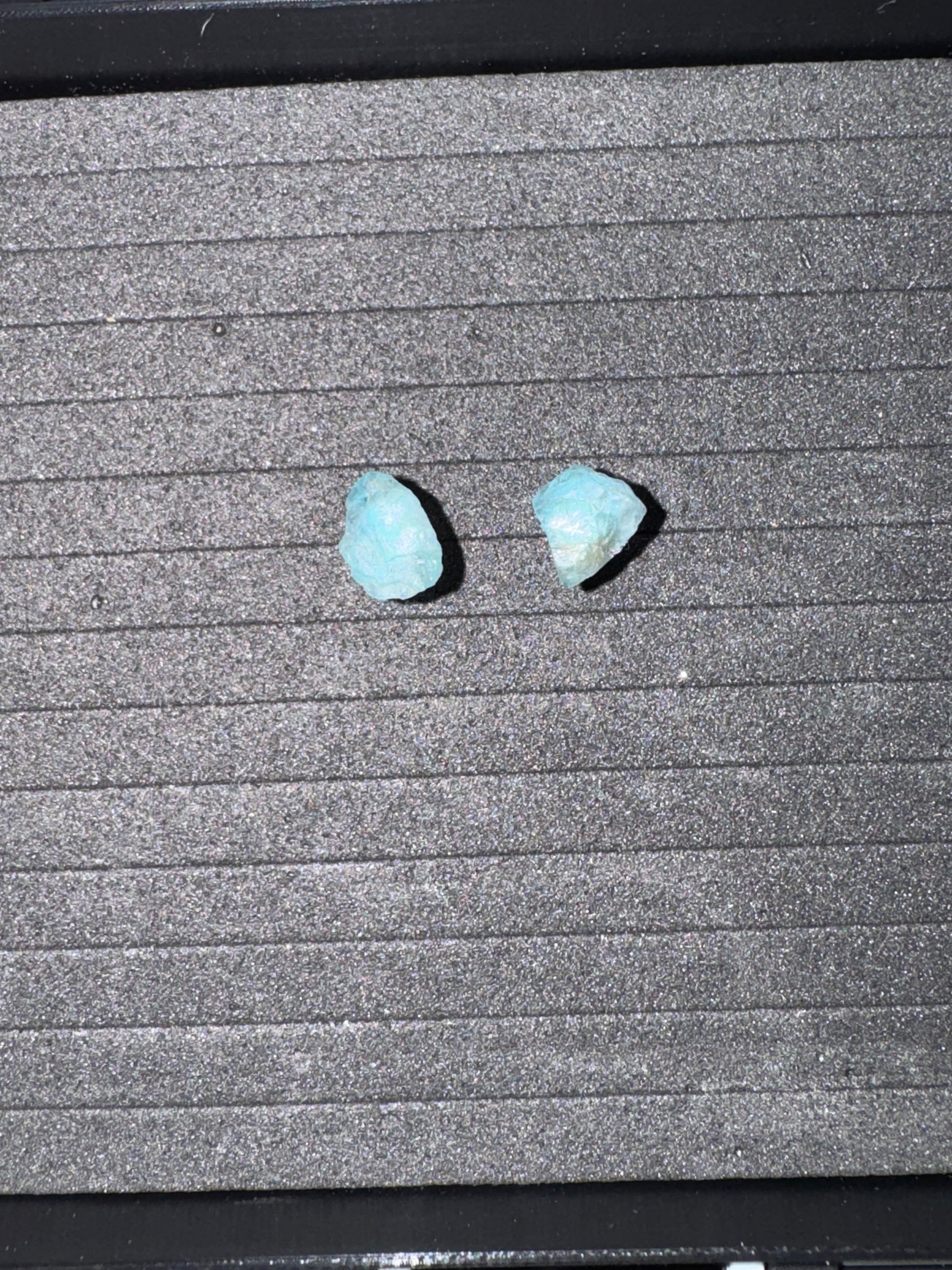 Two blue stones on a textured gray surface
