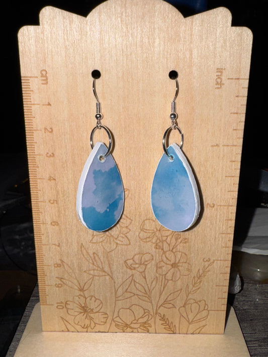 Teardrop-shaped earrings on a wooden display card with floral design and measurement scale.