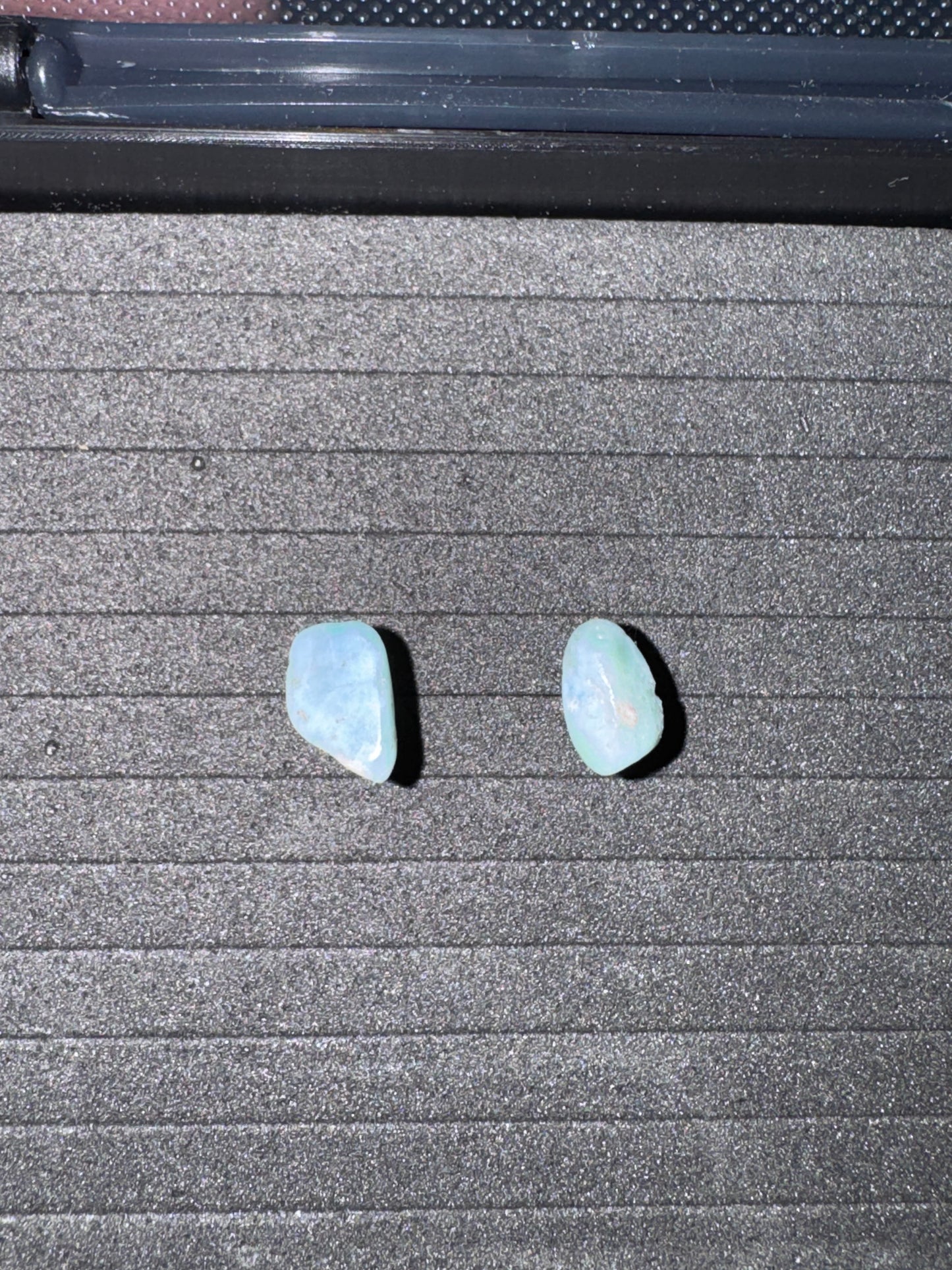 Two light blue stones on a textured gray surface