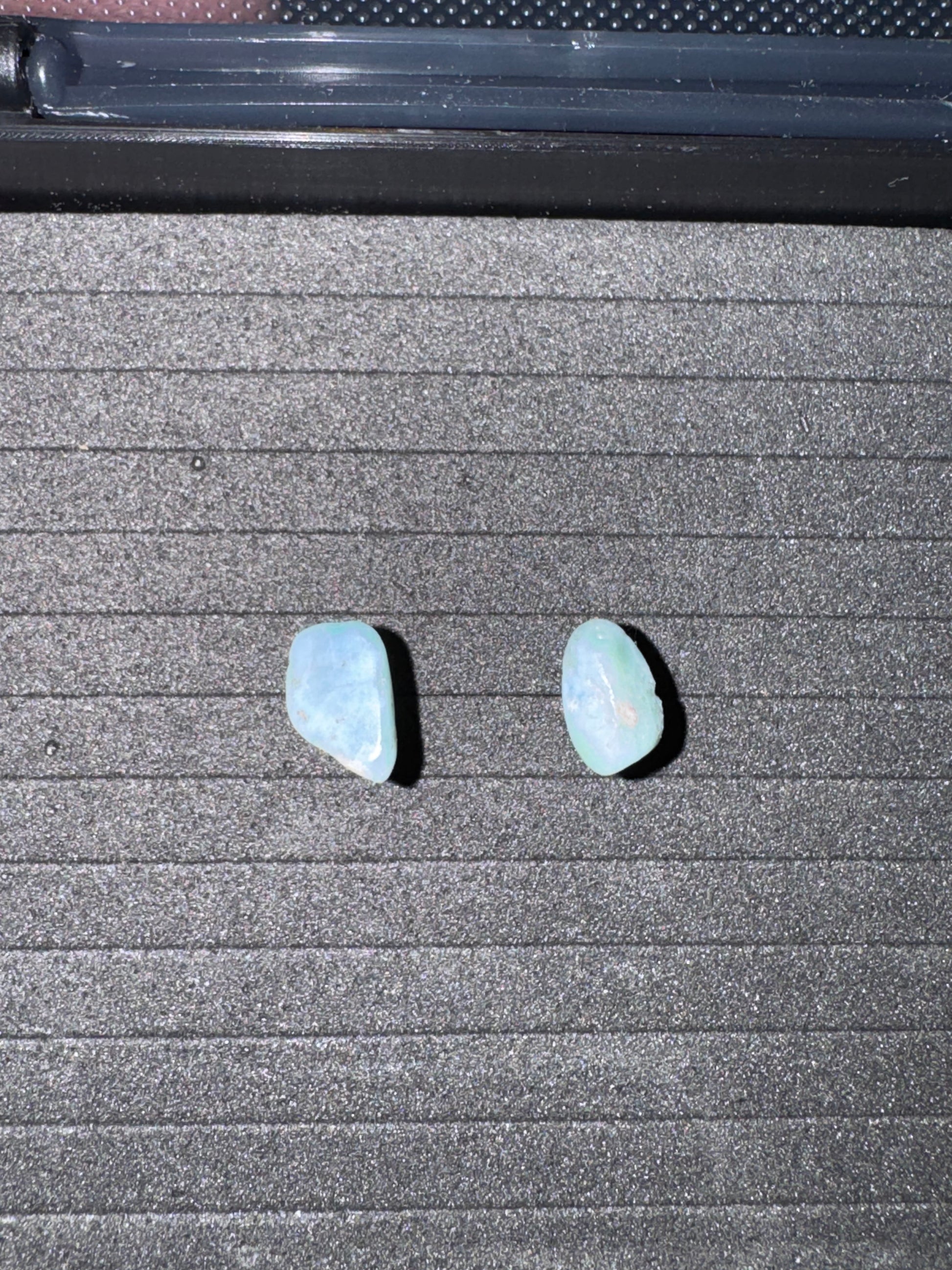 Two light blue stones on a textured gray surface