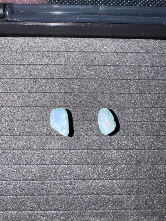Two light blue stone earrings on a textured gray surface