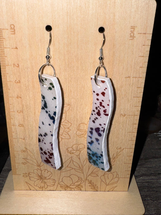 Earrings with a spotted pattern on a wooden surface with measurement markings.