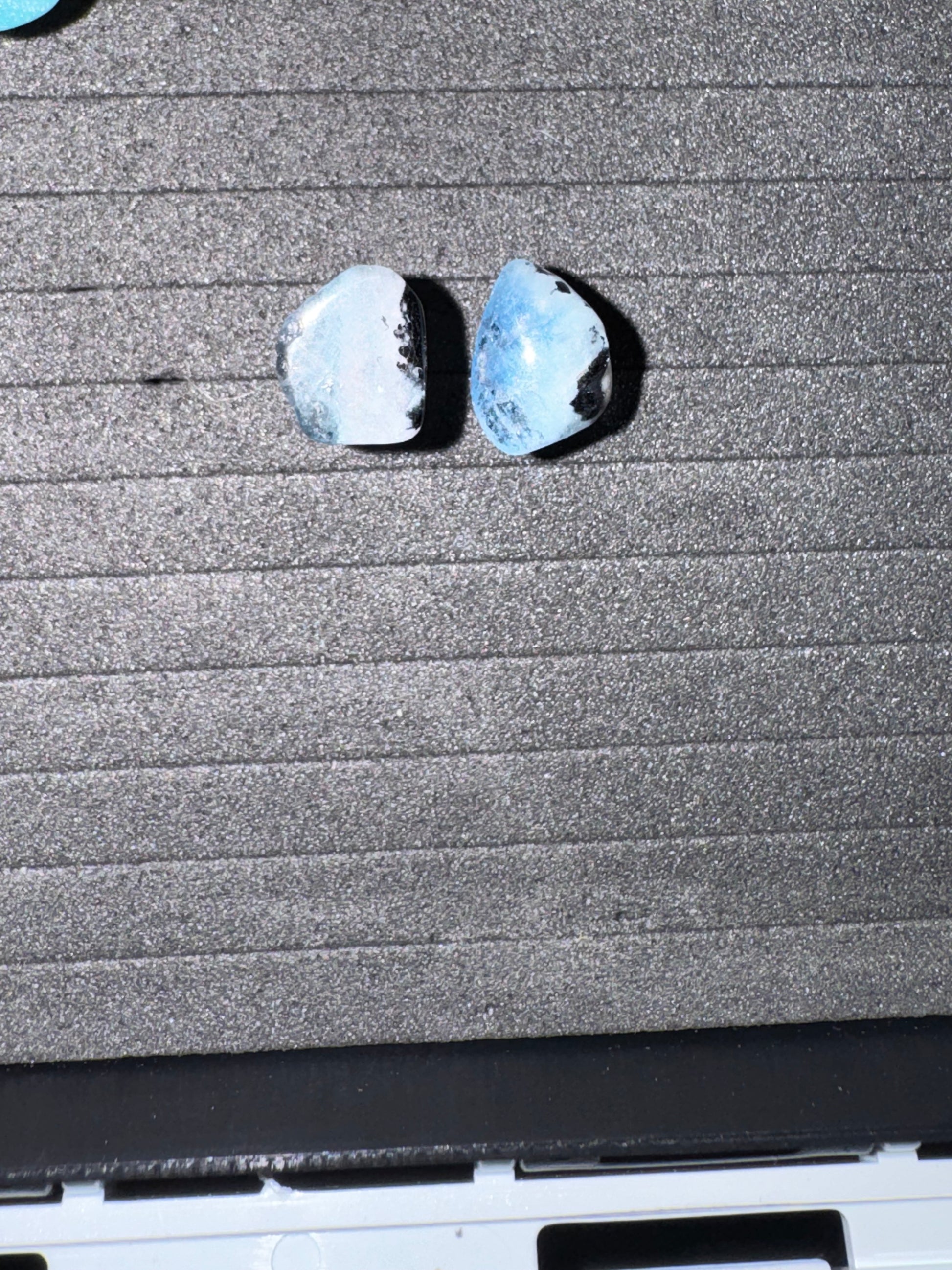 Two earrings on a textured gray surface with a blurred background