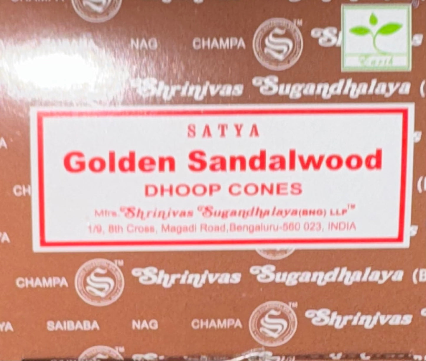 A close-up of a brown box of Satya Golden Sandalwood Dhoop Cones, featuring a white label with red text and a green 'Scenti' logo in the top right corner.
