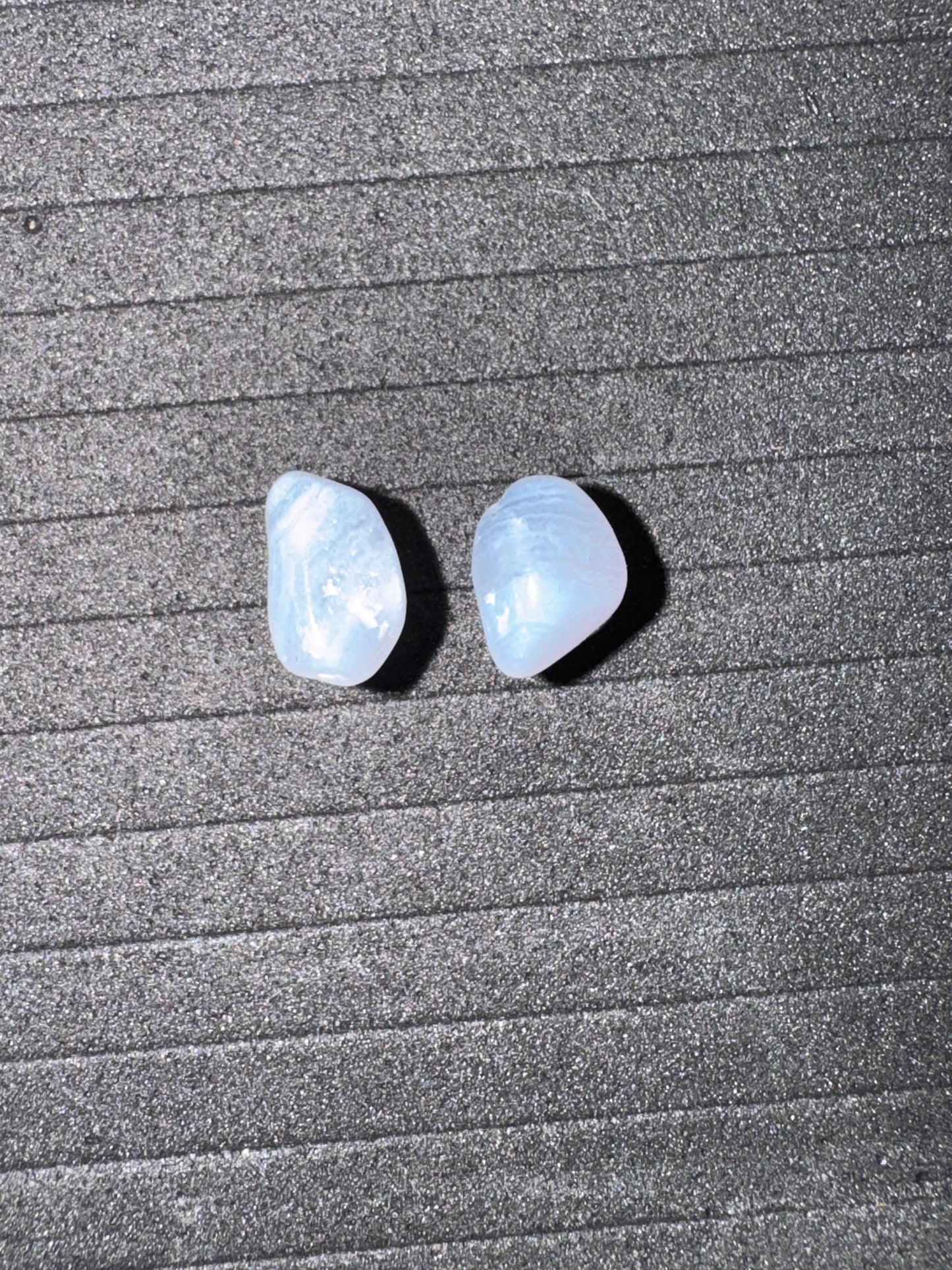 Two light blue stones on a textured gray surface