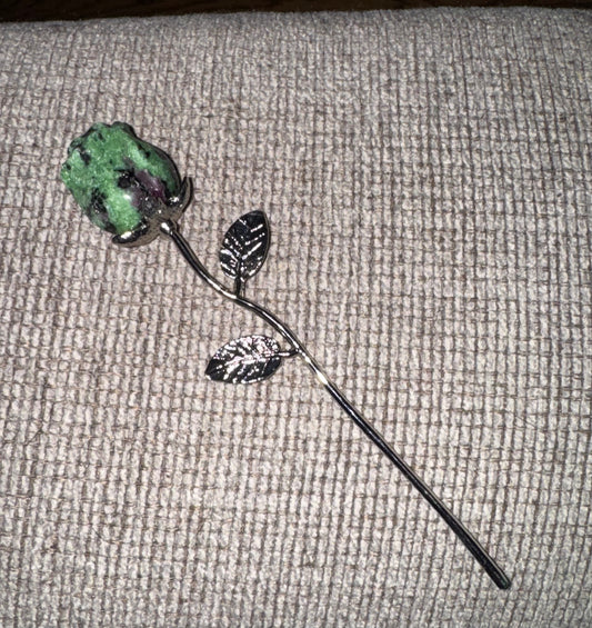 Decorative rose with green stone on a gray textured surface