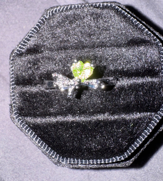Silver ring with a green gemstone in a black velvet ring box on a gray background