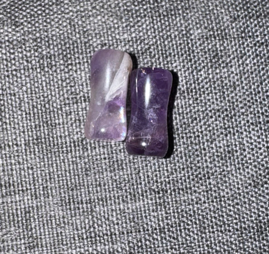 Two purple crystal stones on a textured gray surface