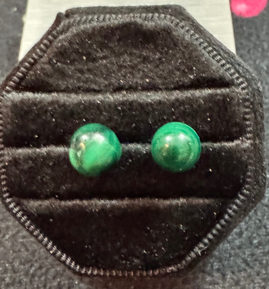 Pair of green stud earrings on a black velvet stand.