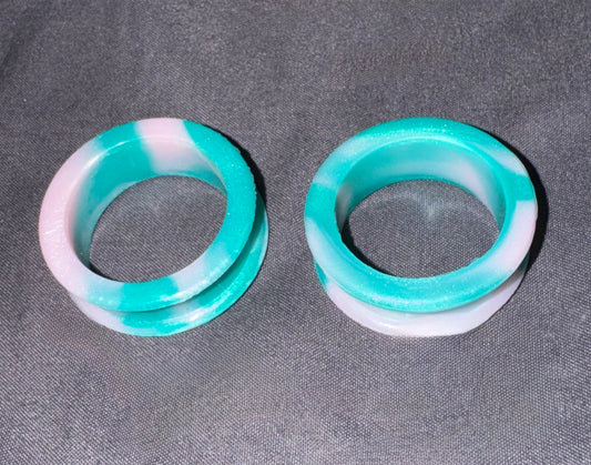 Two round plug earrings made of marbled turquoise and white resin, displayed on a textured gray fabric background.