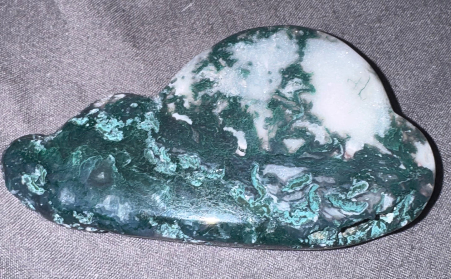 Green and white stone on a gray fabric background