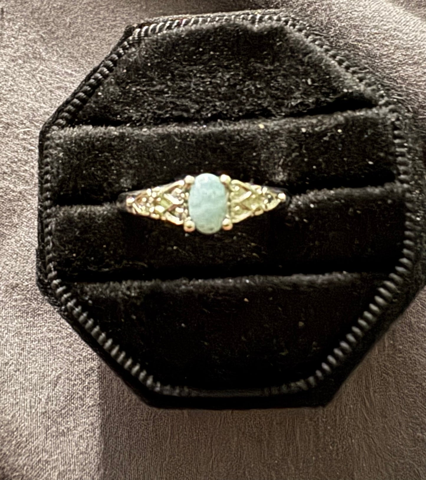 Gold ring with a turquoise stone on a black velvet cushion