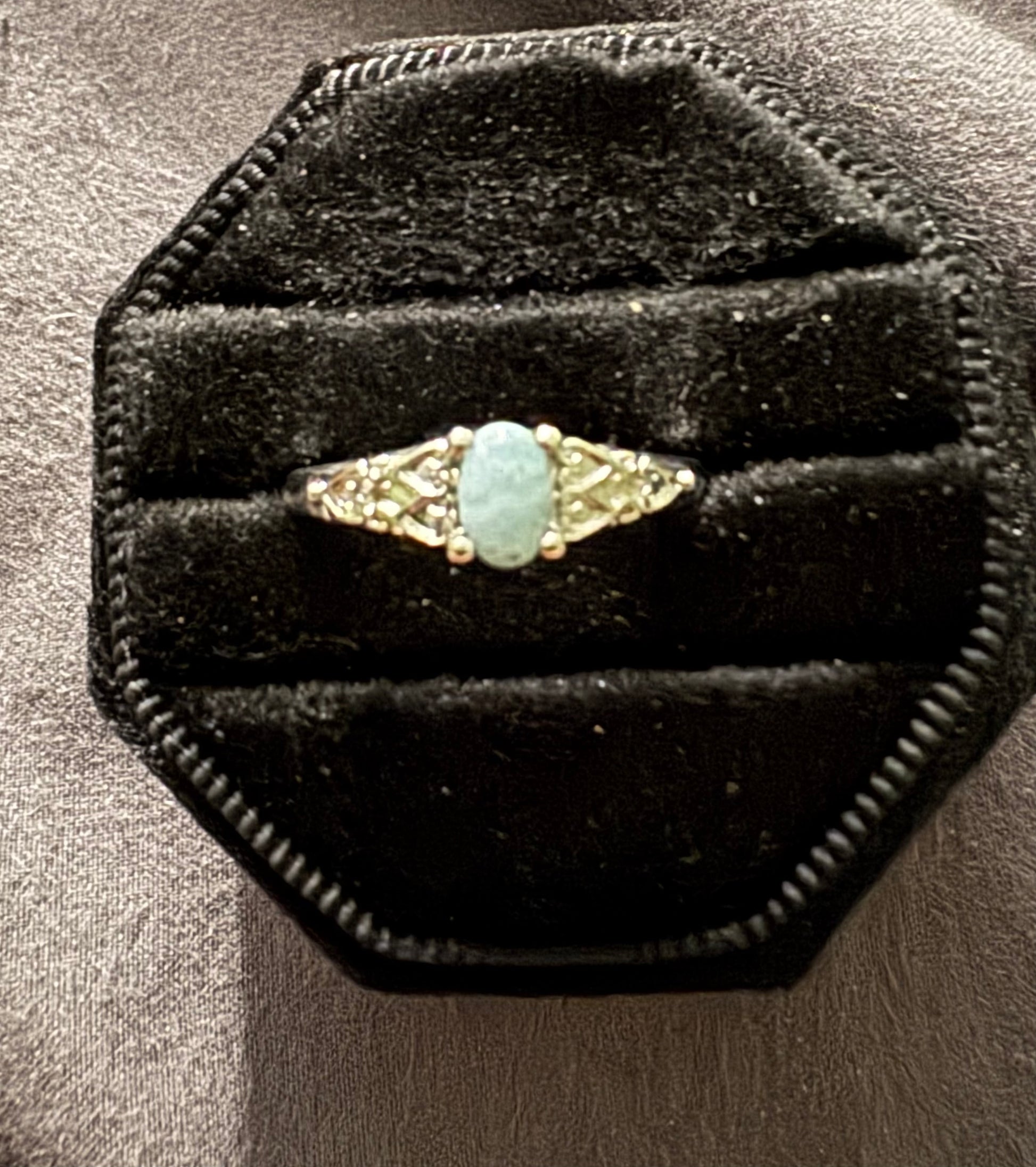 Gold ring with a turquoise stone on a black velvet cushion
