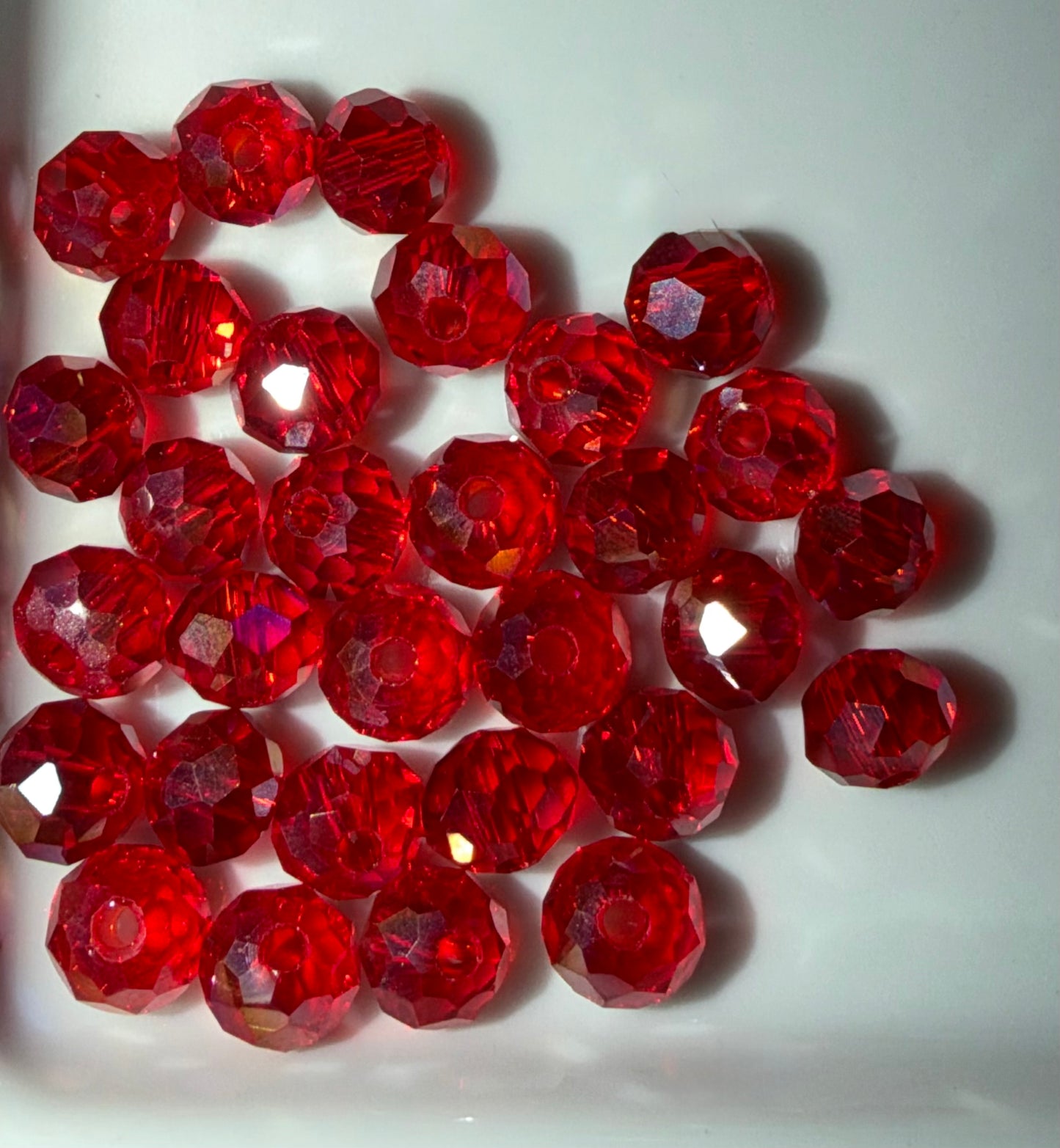 A pile of faceted red glass beads on a plain white background.