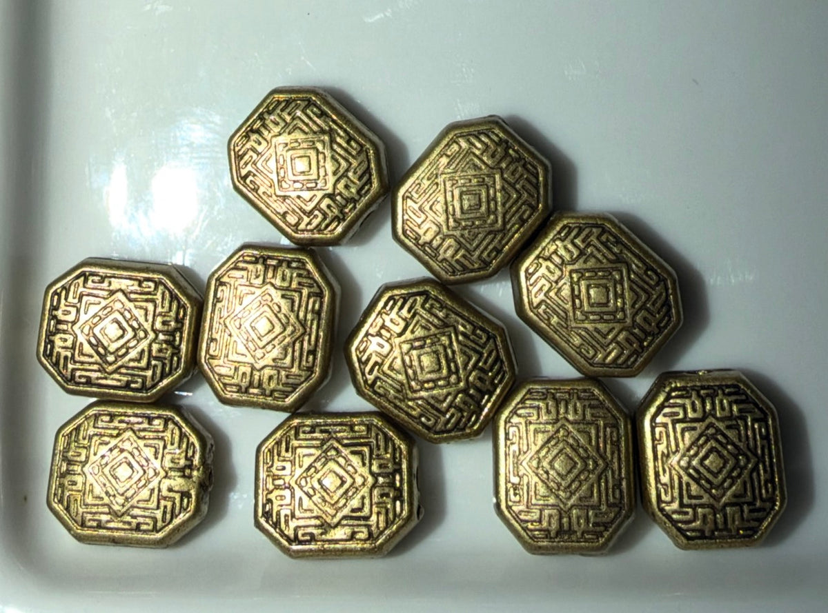 Ten metallic gold-toned octagonal beads with embossed geometric patterns, arranged on a white surface.