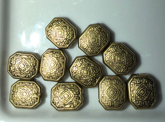 Ten metallic gold-toned octagonal beads with embossed geometric patterns, arranged on a white surface.