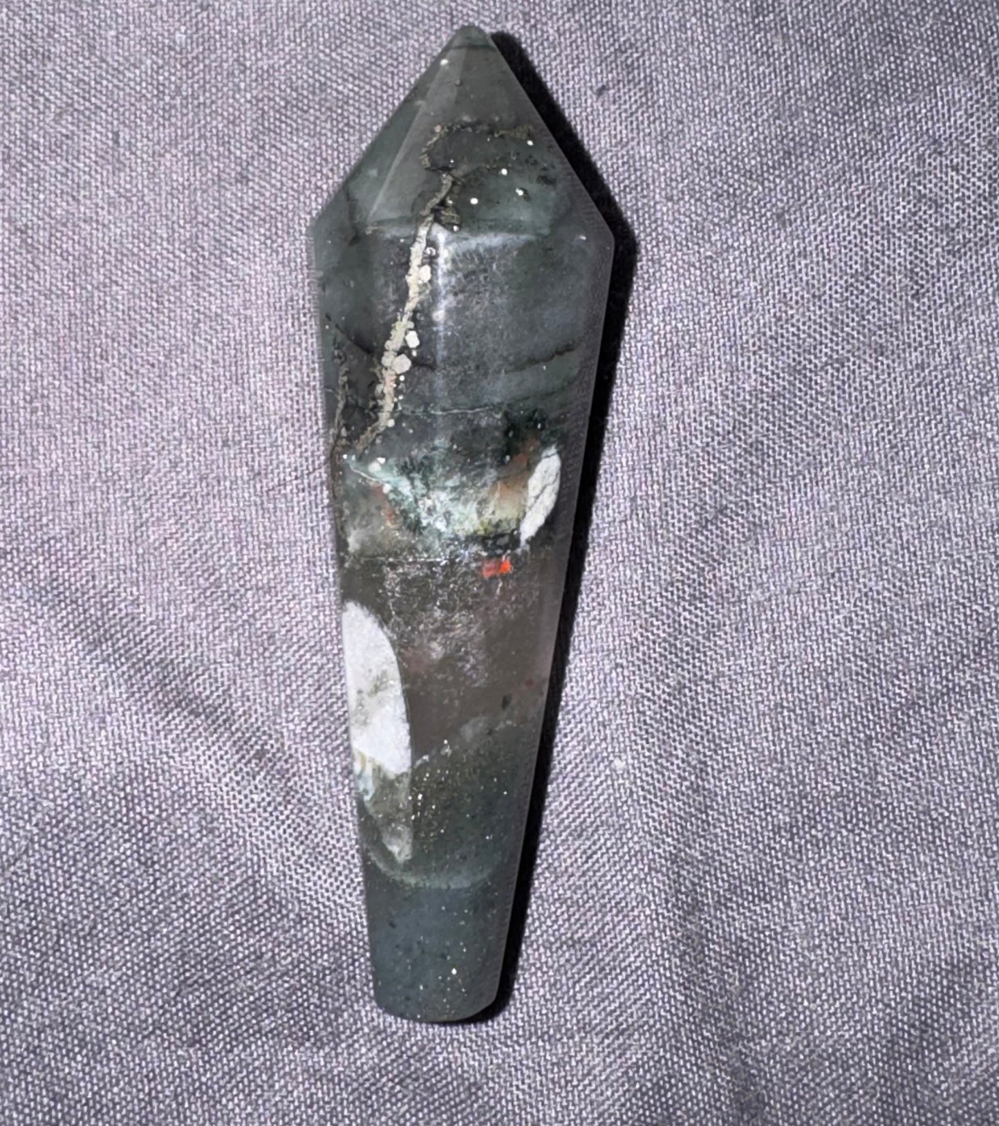 Black crystal or stone on a gray fabric background