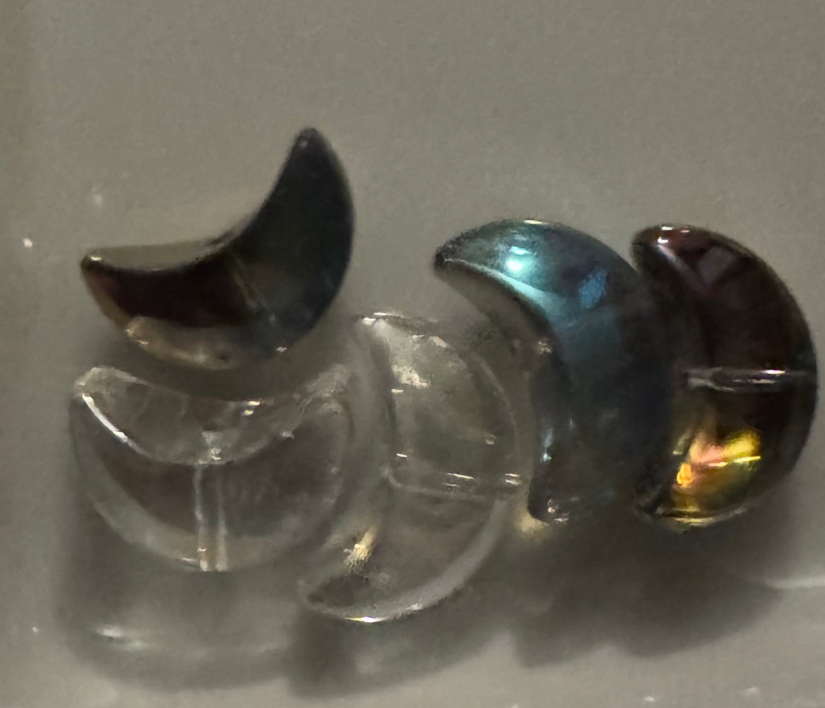 Small crescent moon-shaped beads displayed   against a plain light background. 