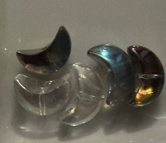 Small crescent moon-shaped beads displayed   against a plain light background. 