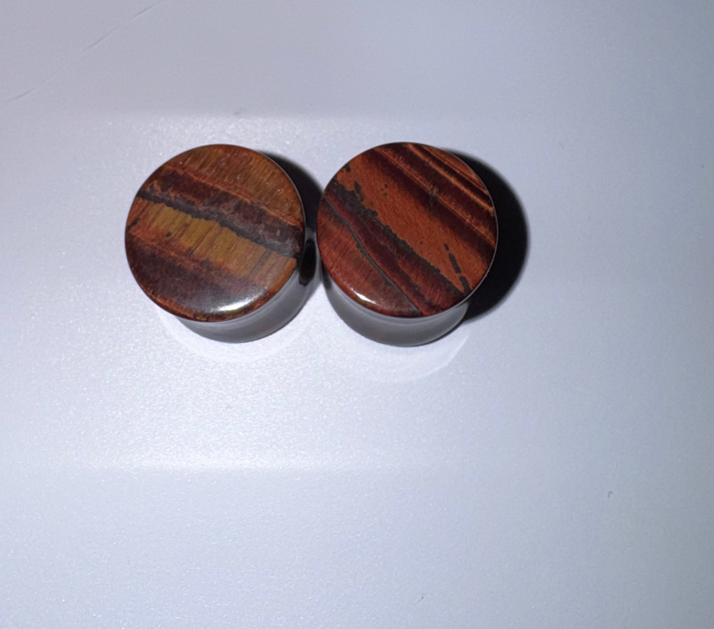 Two red Tigers eyes objects with a striped pattern on a white background