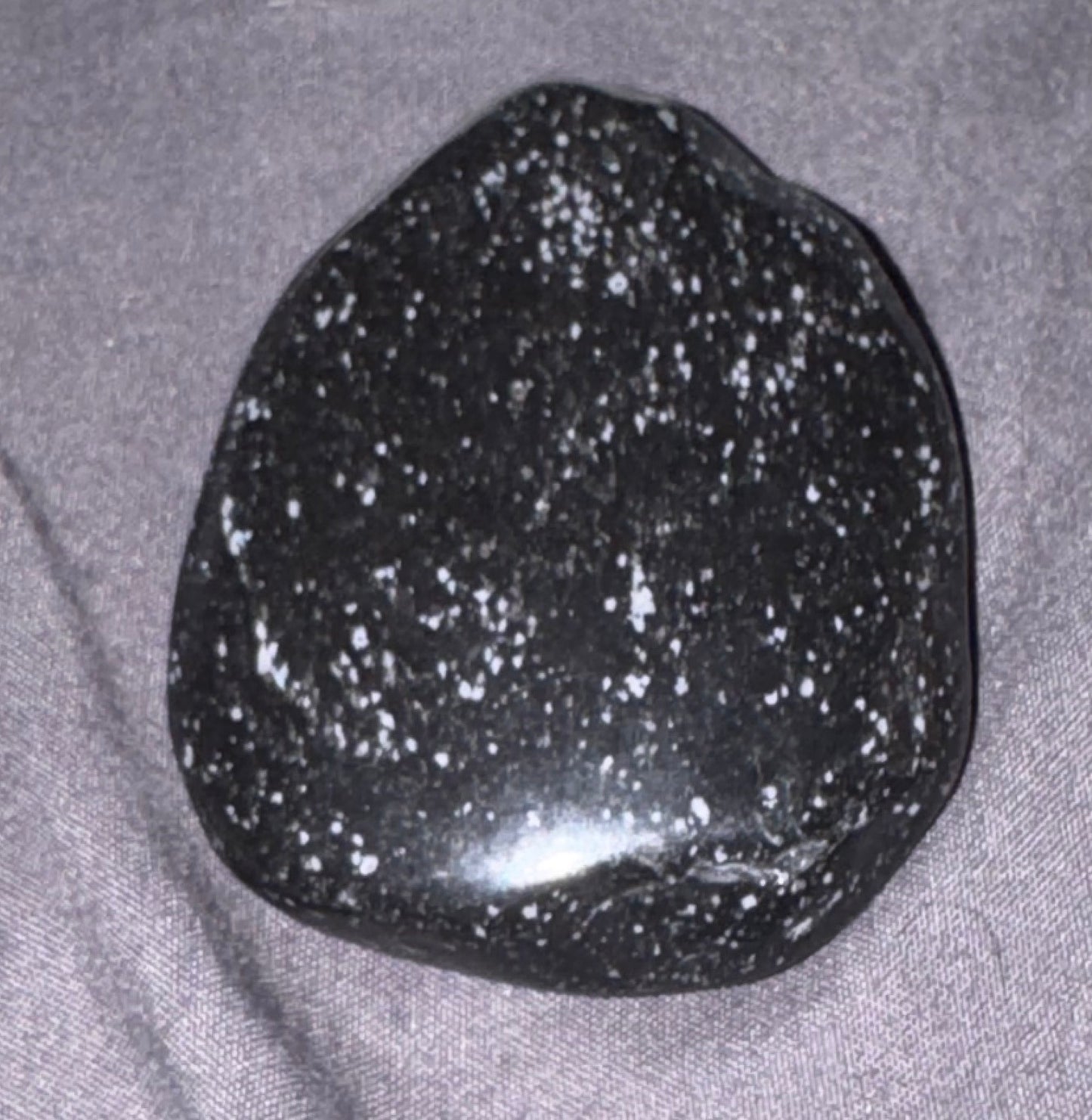 Black speckled stone on a gray fabric background
