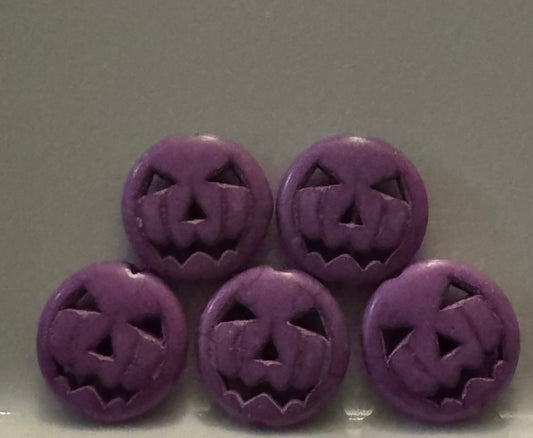 Five round purple jack-o'-lantern face beads arranged in two rows on a plain gray background.