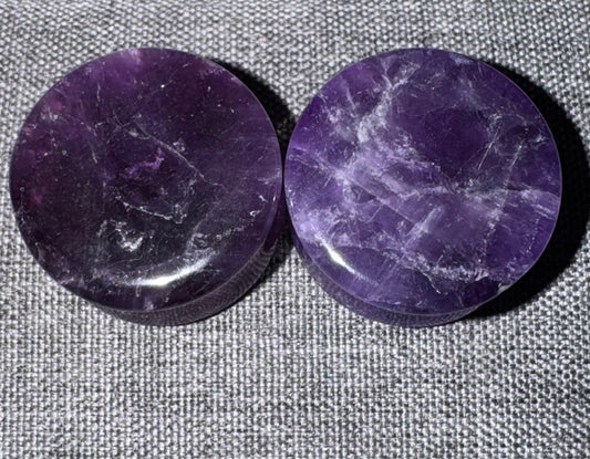 Two purple stone discs on a textured gray background