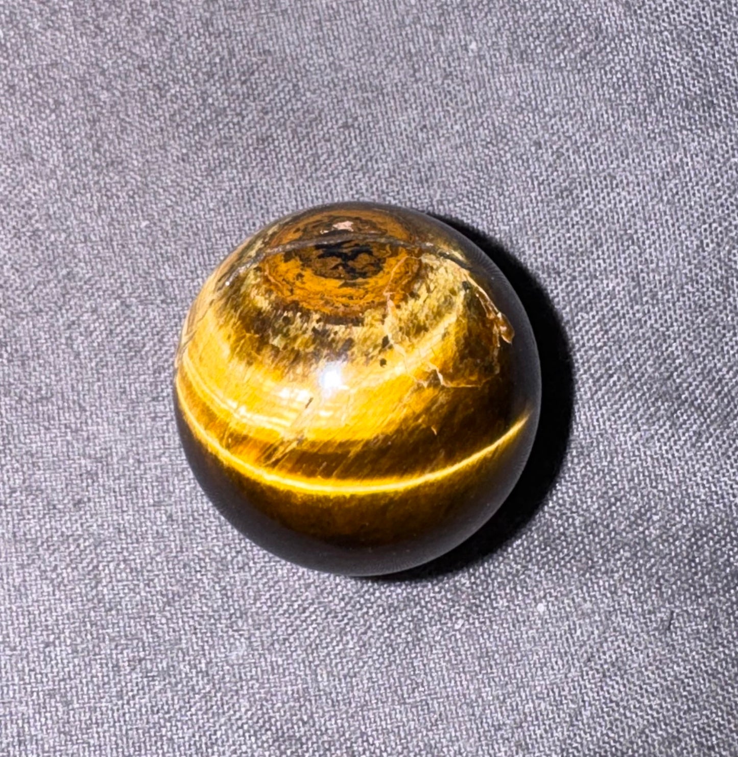 Round amber-colored stone on a gray fabric background