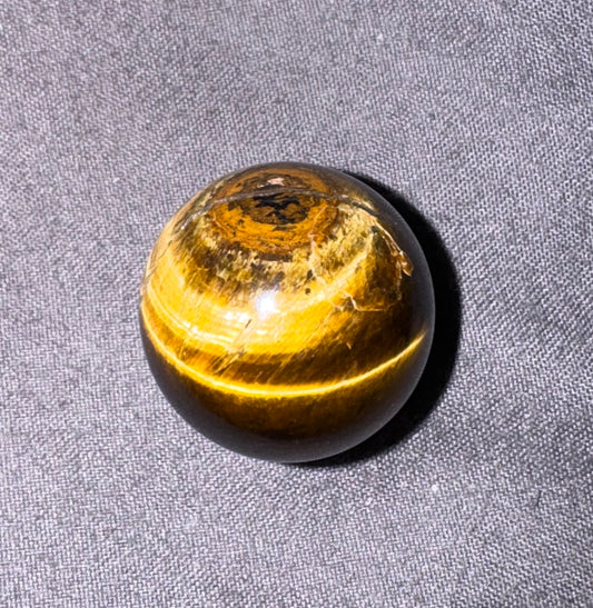 Round amber-colored stone on a gray fabric background