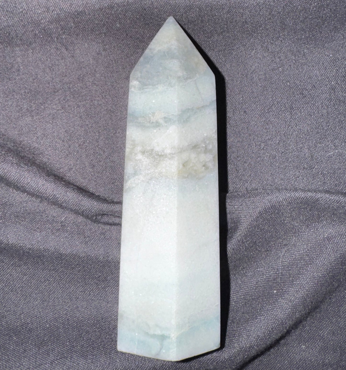 Marble-like crystal obelisk on a gray fabric background