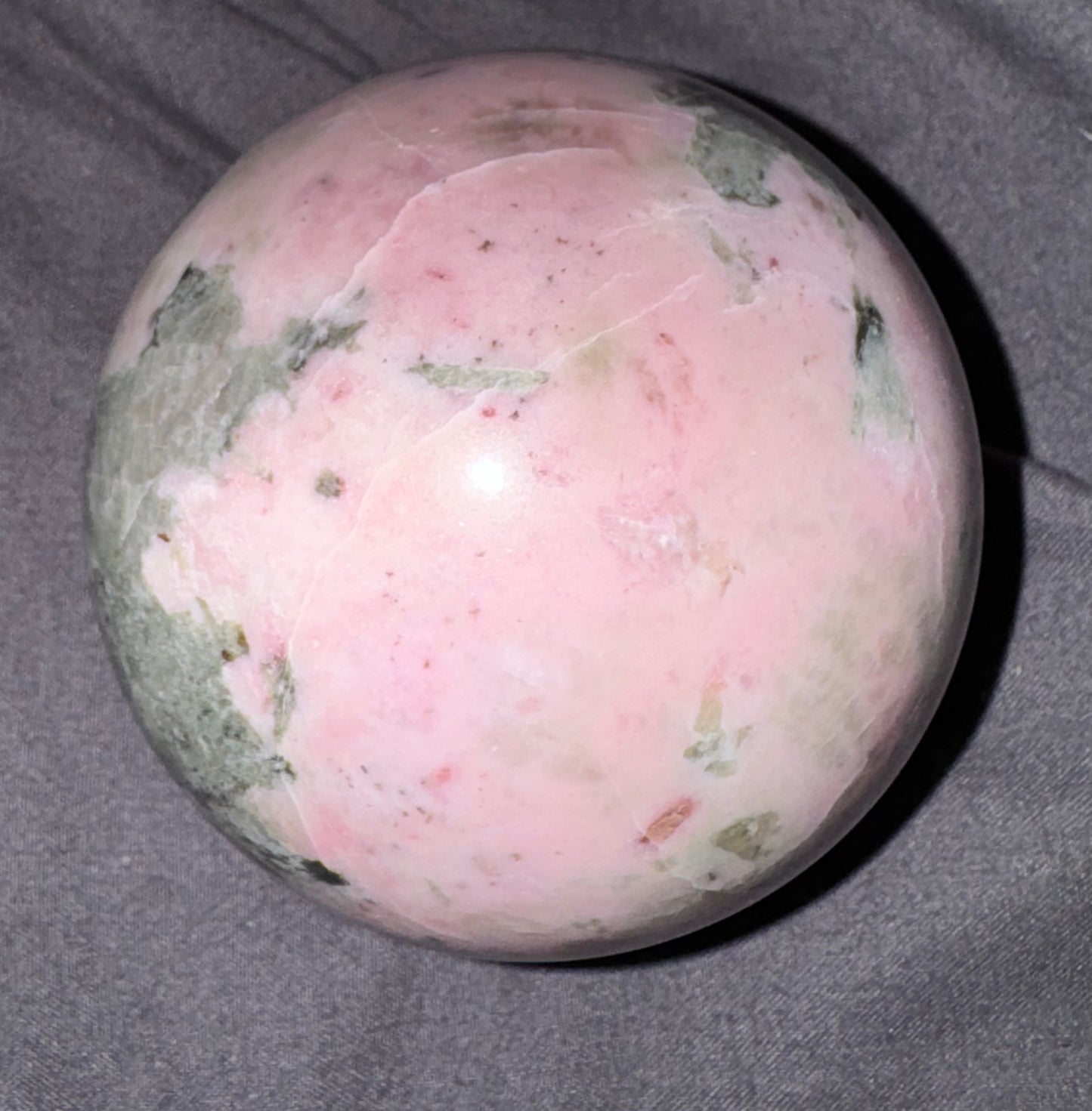 Pink and green marbled sphere on a gray background