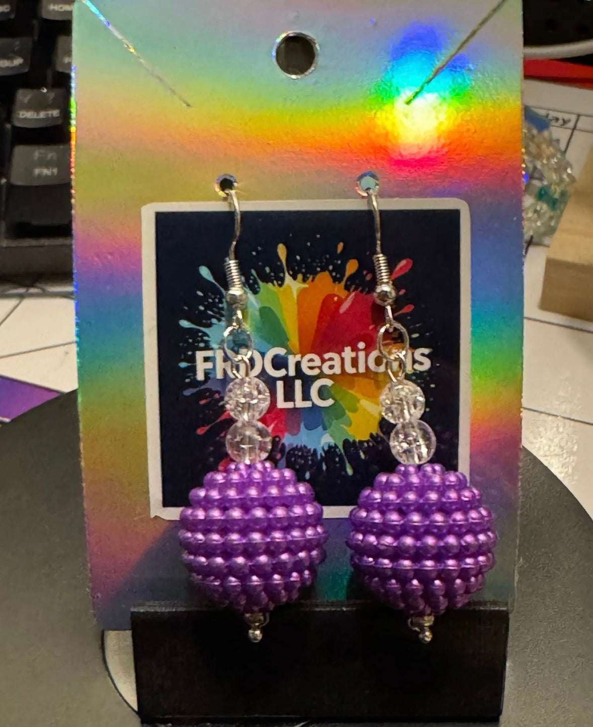 Purple beaded earrings on a colorful card.