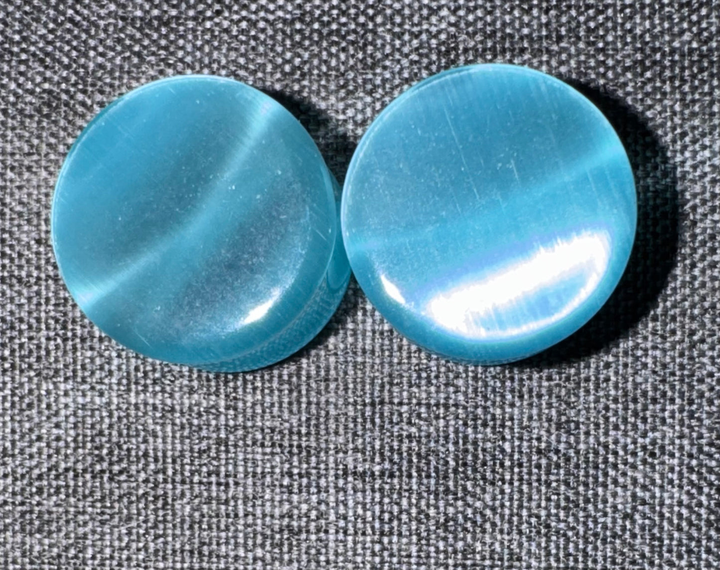 Two blue ear gauges on a textured gray background