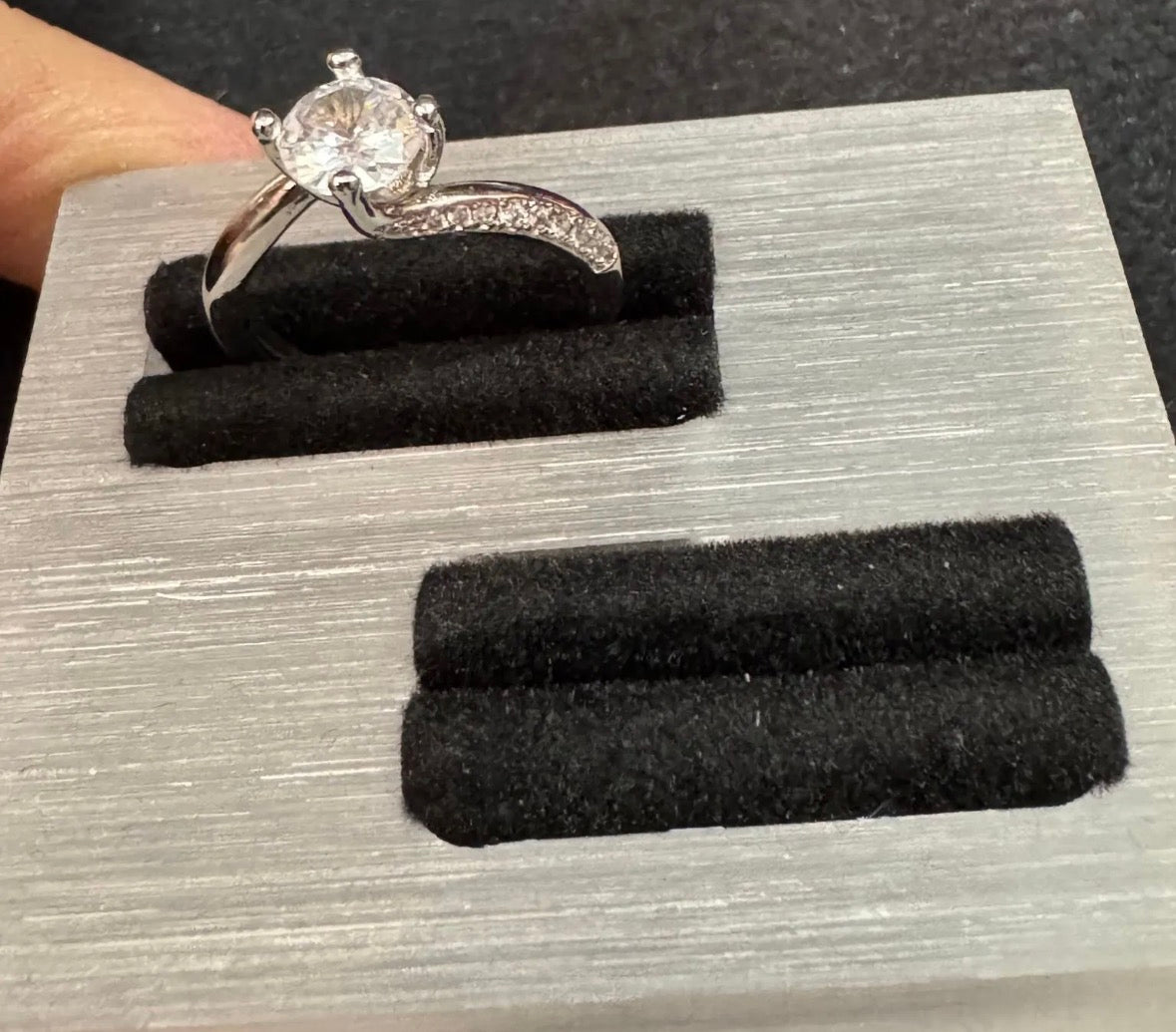 Silver ring with a diamond on a gray display stand