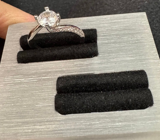 Silver ring with a diamond on a gray display stand