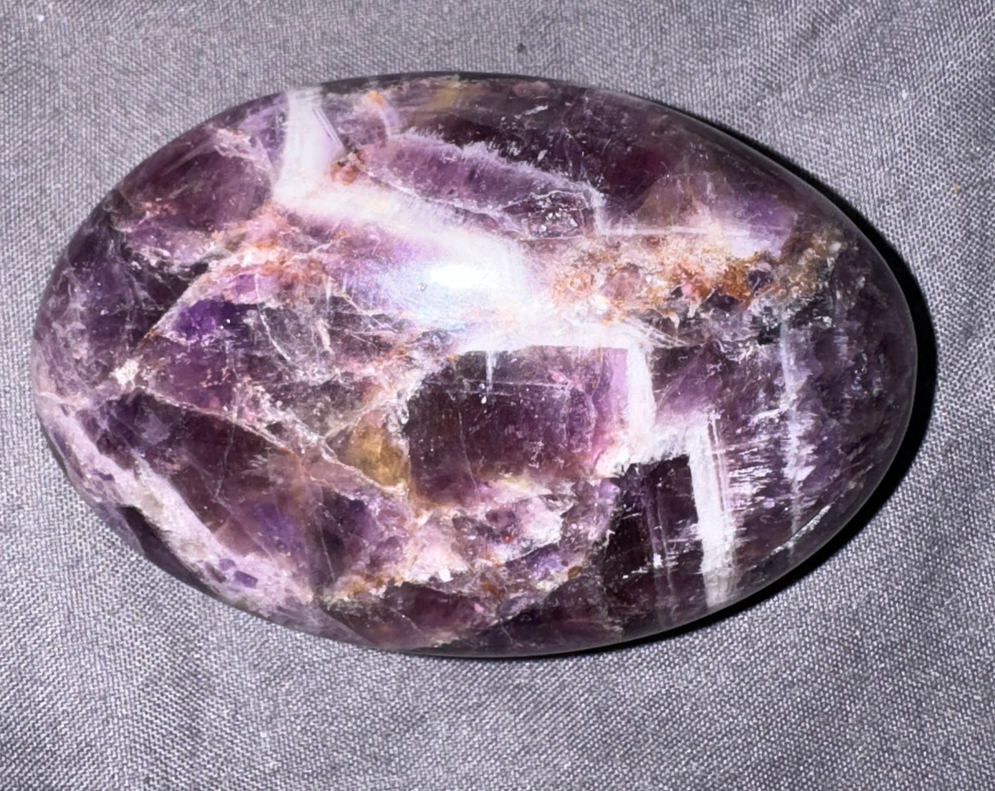 Polished amethyst crystal on a gray fabric background