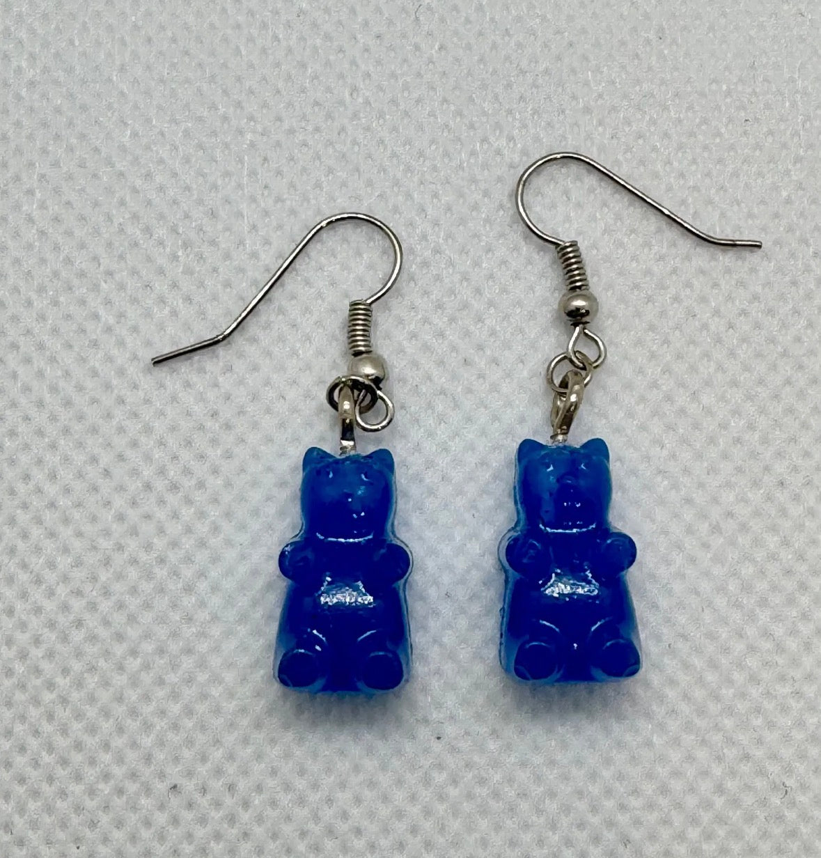 Blue gummy bear-shaped earrings on a light gray background