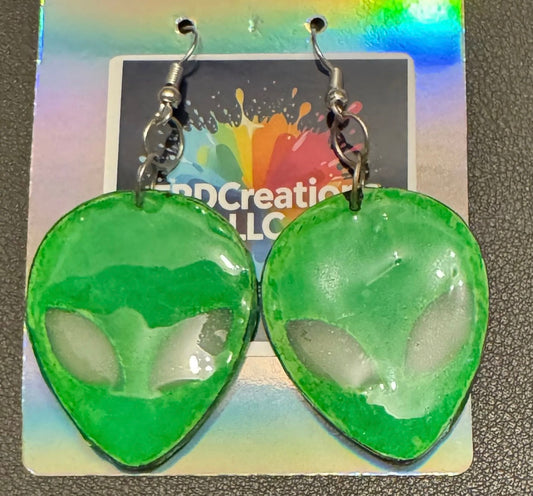 Green alien head earrings on a colorful card