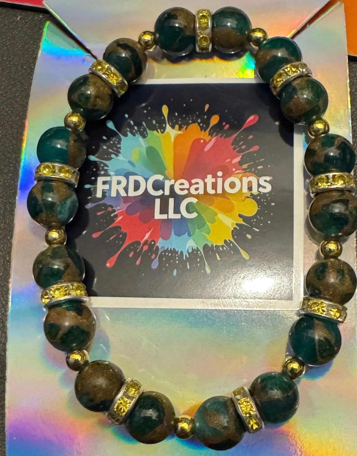 Green beaded bracelet with gold accents on a colorful card with 'FRDCreations LLC' branding.