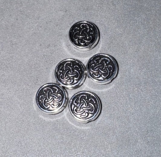 Five round silver-toned metal buttons with an interlaced Celtic knot design, arranged on a textured gray background.