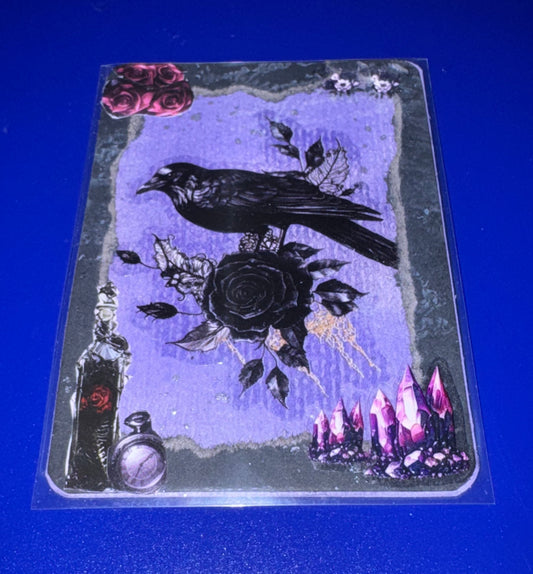 Decorative card with a crow, rose, and mystical elements on a blue background