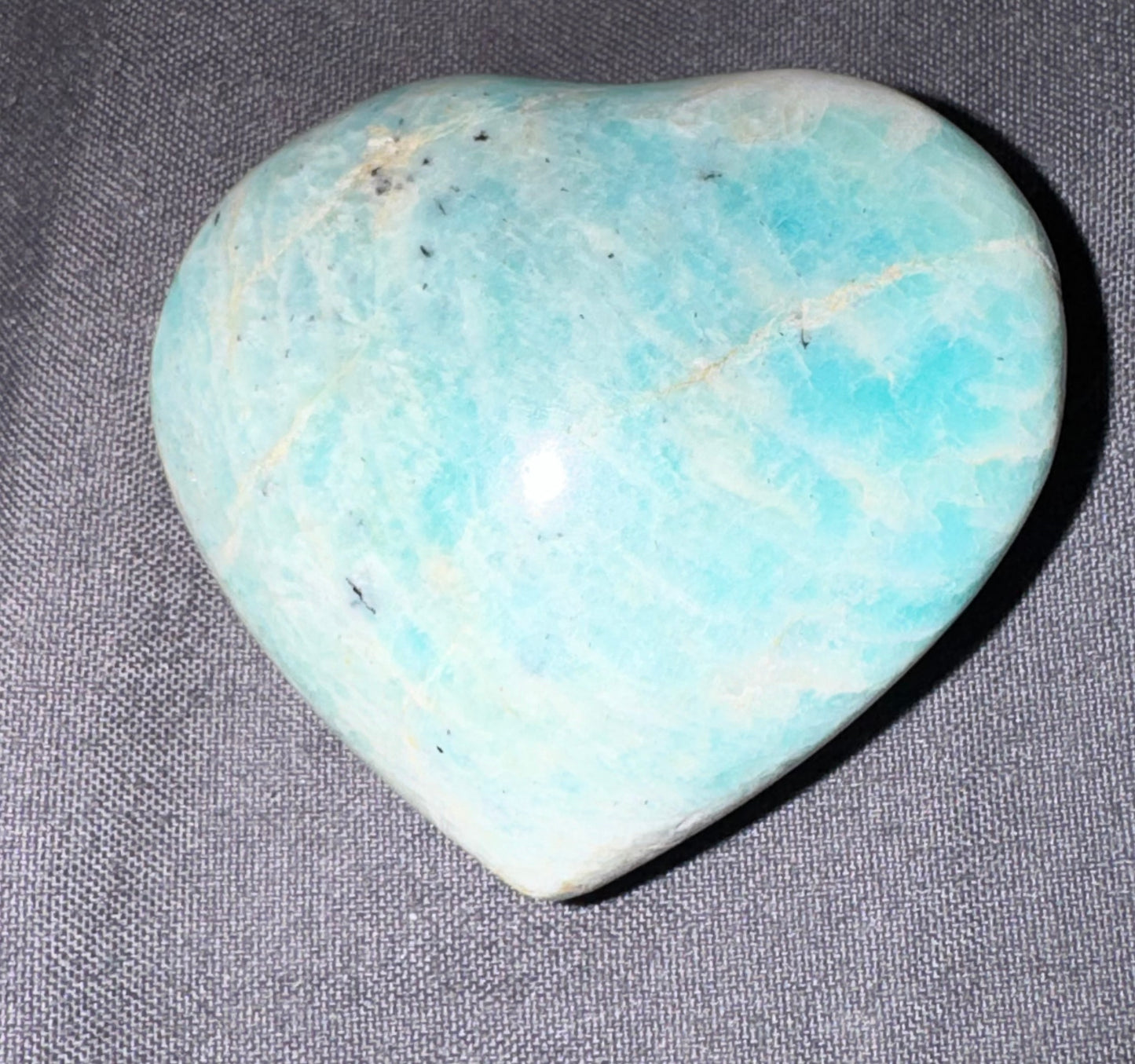 Heart-shaped turquoise stone on a gray fabric background