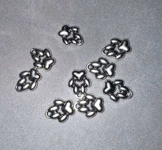 Five small metallic paw print charms arranged on a light gray textured background.