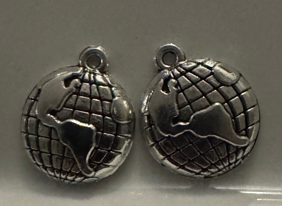 Two silver globe charms with raised continents and a grid pattern, shown on a plain gray background.