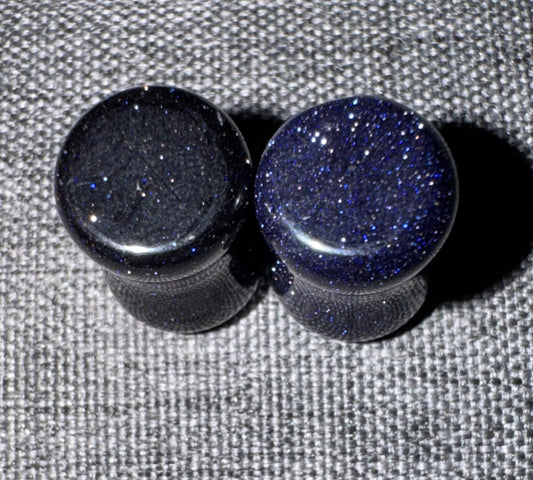 Two black and blue glittery knobs on a textured gray background