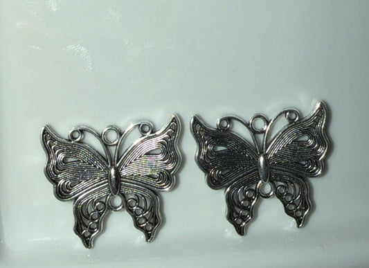 Two silver butterfly-shaped jewelry findings or charms displayed side by side on a plain white background.