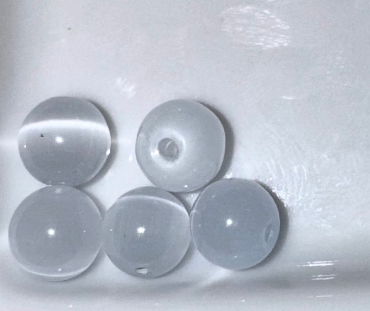 Five translucent white glass beads with a smooth, glossy finish, arranged on a white surface.