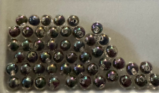 A group of small round iridescent beads with a metallic silver base and rainbow reflections, arranged on a plain light background.